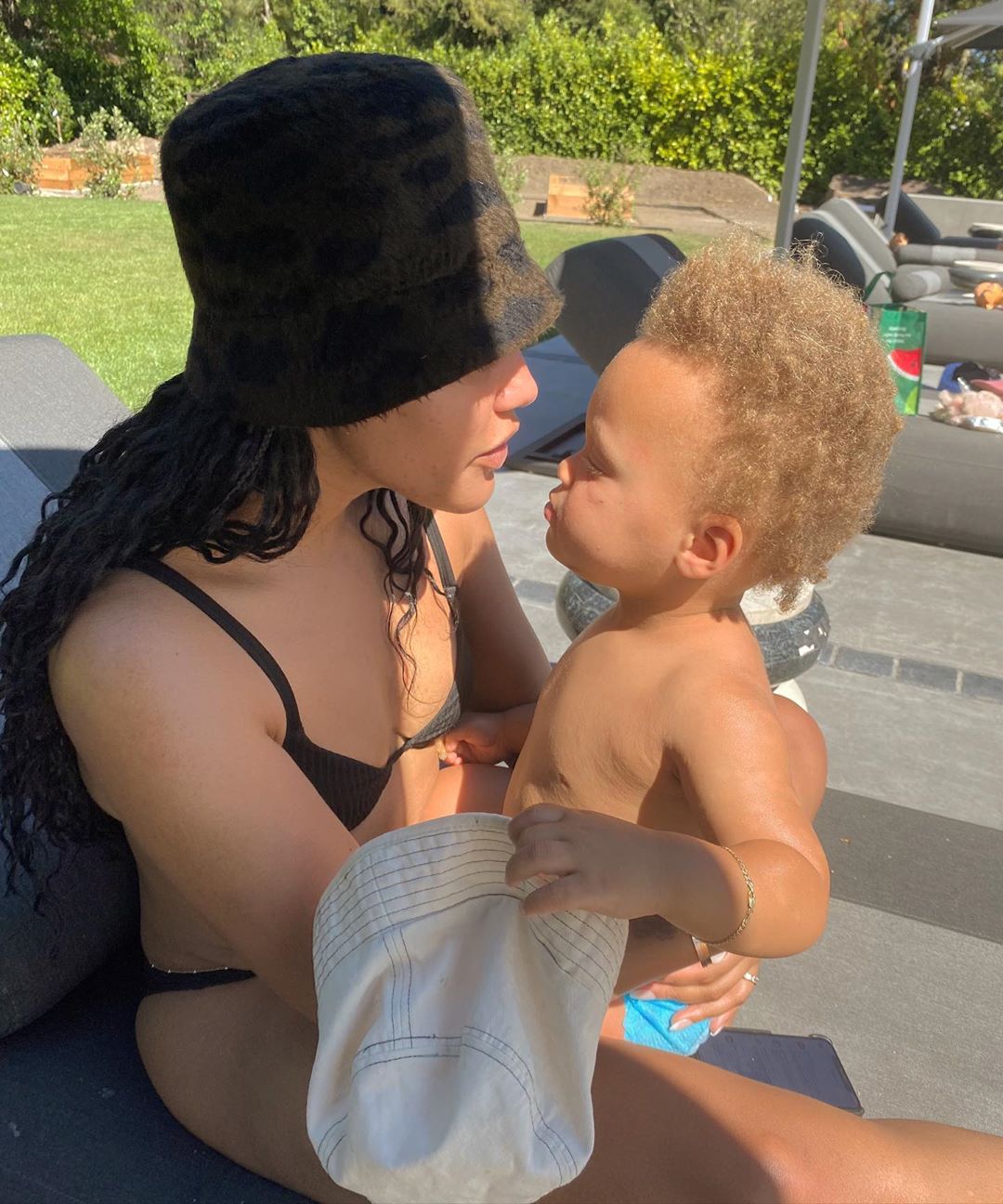 Ayesha Curry and Son Canon Sit by The Pool Ayesha Wears Bucket Hat and Black Bikini