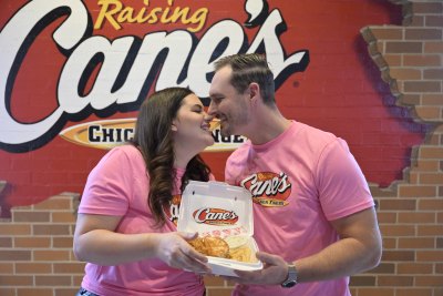 Love Is Blind's Alexa and Brennon Lemieux kiss while holding a box of Raising Cane's chicken tenders